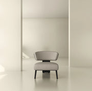 Modern minimalist lounge chair with light upholstery and black legs in a neutral interior.